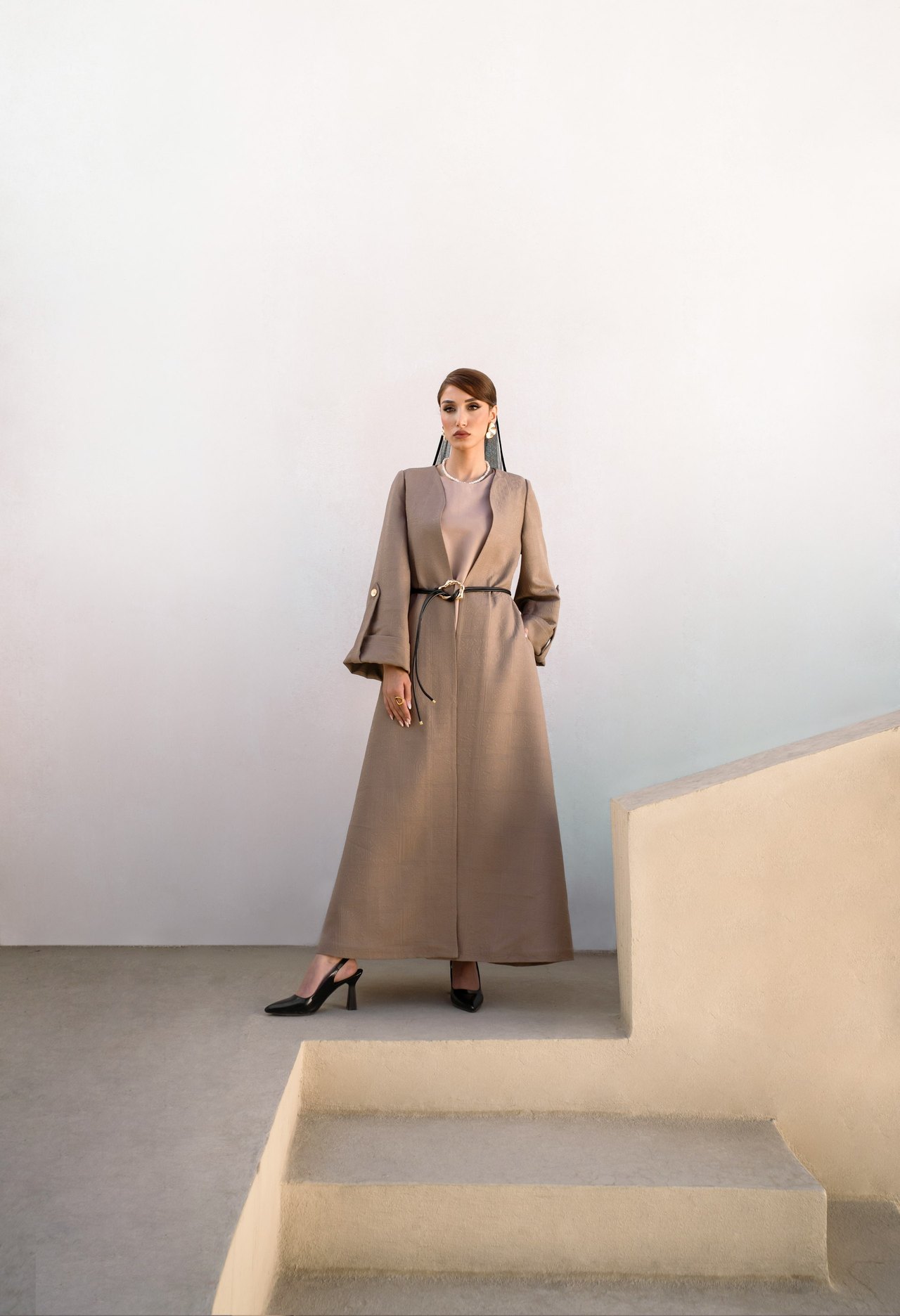 Model in beigem Mantel auf einer Treppe